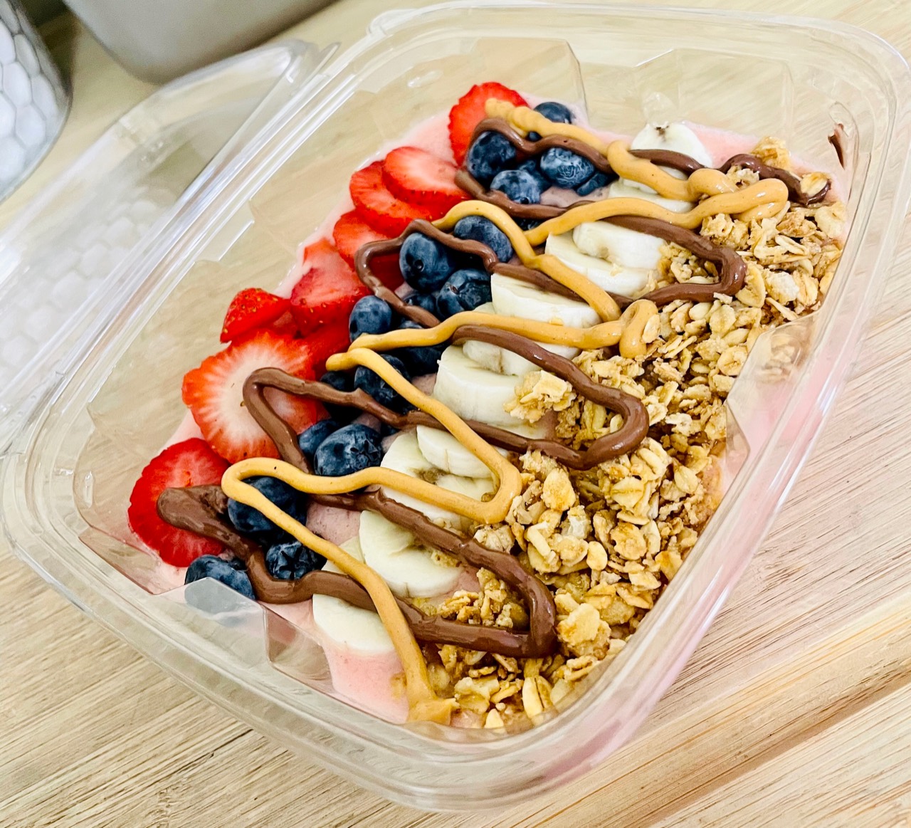 Playa Bowl topped with sliced strawberries, blueberries, banana, granola, and creamy drizzles
